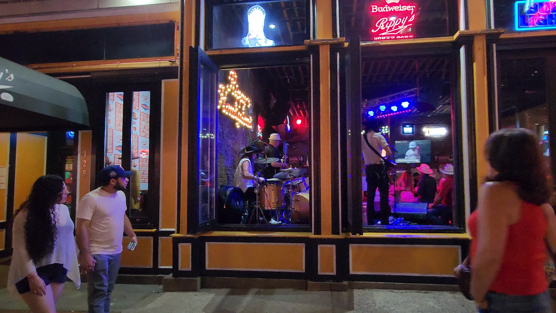 Live music is visible from the sidewalk outside a Lower Broadway venue.